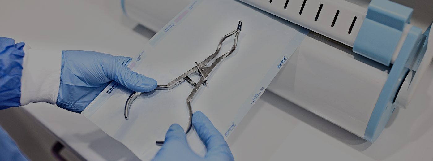 Sterilizing medical instruments in autoclave. Dental office. Close up dentist assistant's hands holding packaged with vacuum packing machine medical instruments ready for sterilizing in autoclave