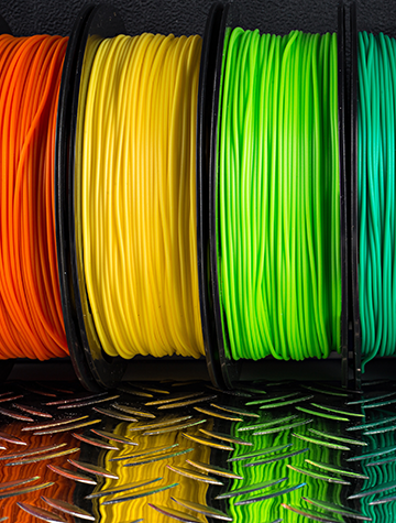 colorful bright row of spool 3D printer filament black metal background