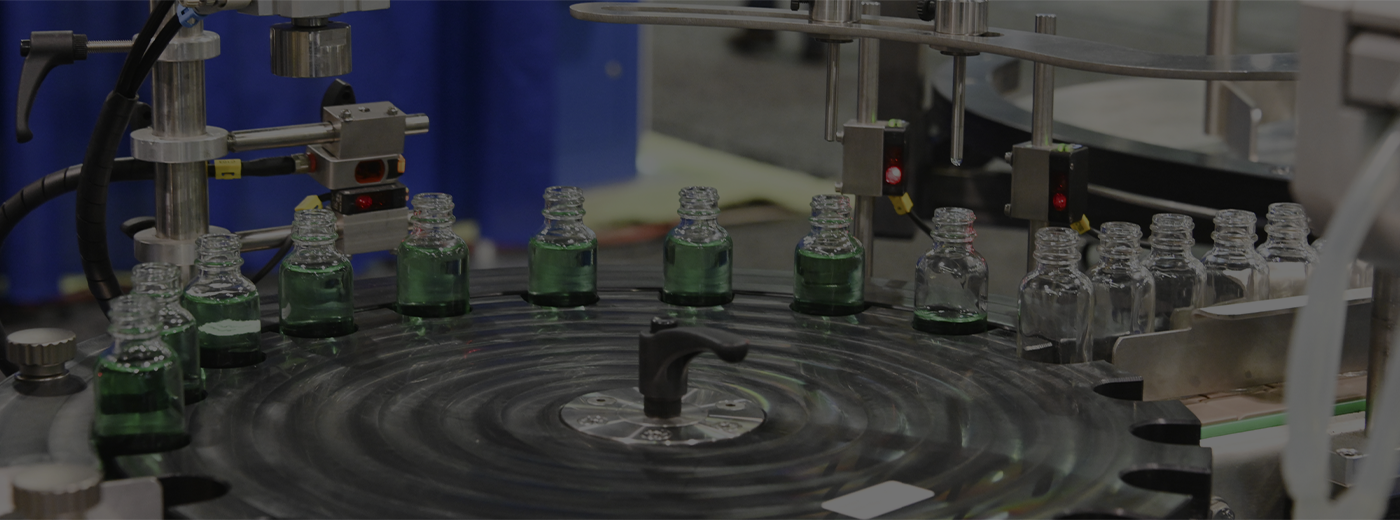 Assembly machine filling green liquid into glass bottles