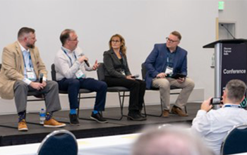 Panel speakers discussing on stage next to Conference Podium