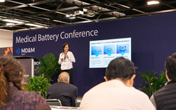 Speaker presenting in front of medical battery conference stage